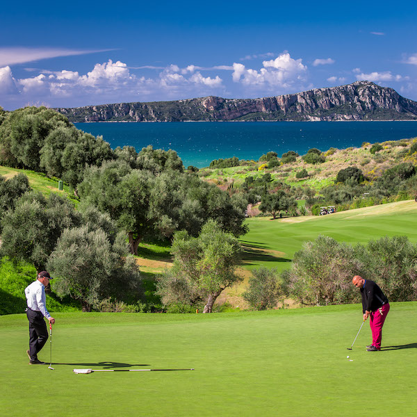 2 golfers putting on a green overlooking the Mediterranean on the Bay Course, Costa Navarino, Greece