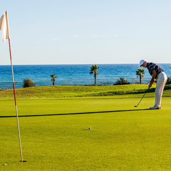 Golfer on Terramar Golf green with sea in the background