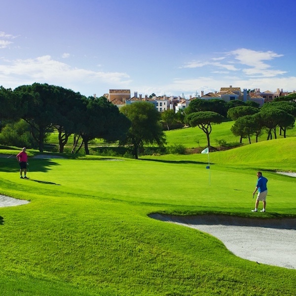 Golfer on Vale do Lobo Golf course with resort accommodation in the background